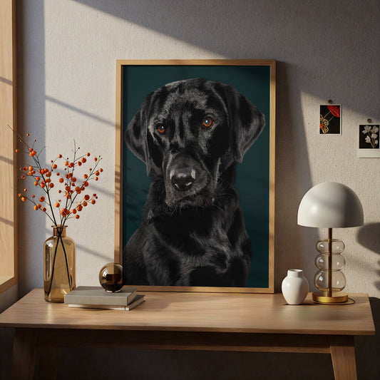 Framed portrait of a black labrador dog on a wooden table with decorative items.