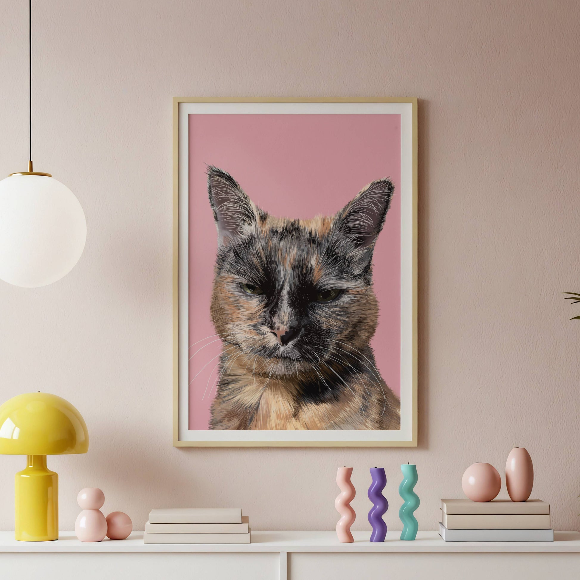 Framed artwork of a cat on a pink background above a white console table with decorative items.